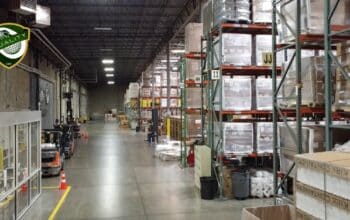 Large warehouse interior with forklifts moving inventory.