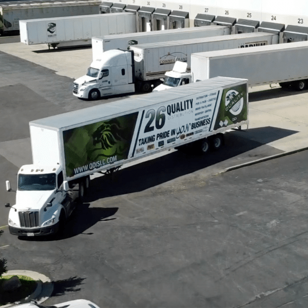 Fleet of delivery trucks loading at a warehouse dock ready for distribution.